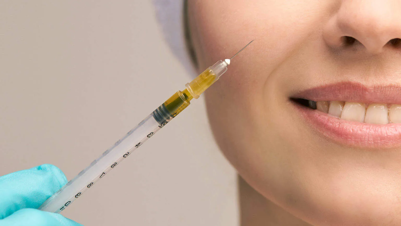 Close-up of syringe for aesthetic injection, Auburn, MA., Experienced aesthetics provider assessing facial features and skin condition with clinical precision
